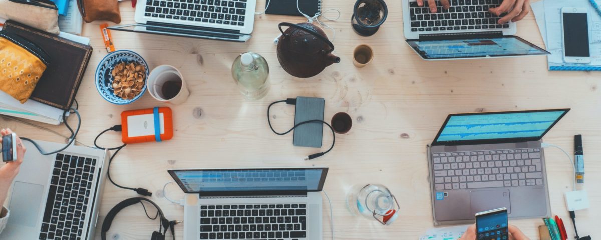 people sitting down near table with assorted laptop computers